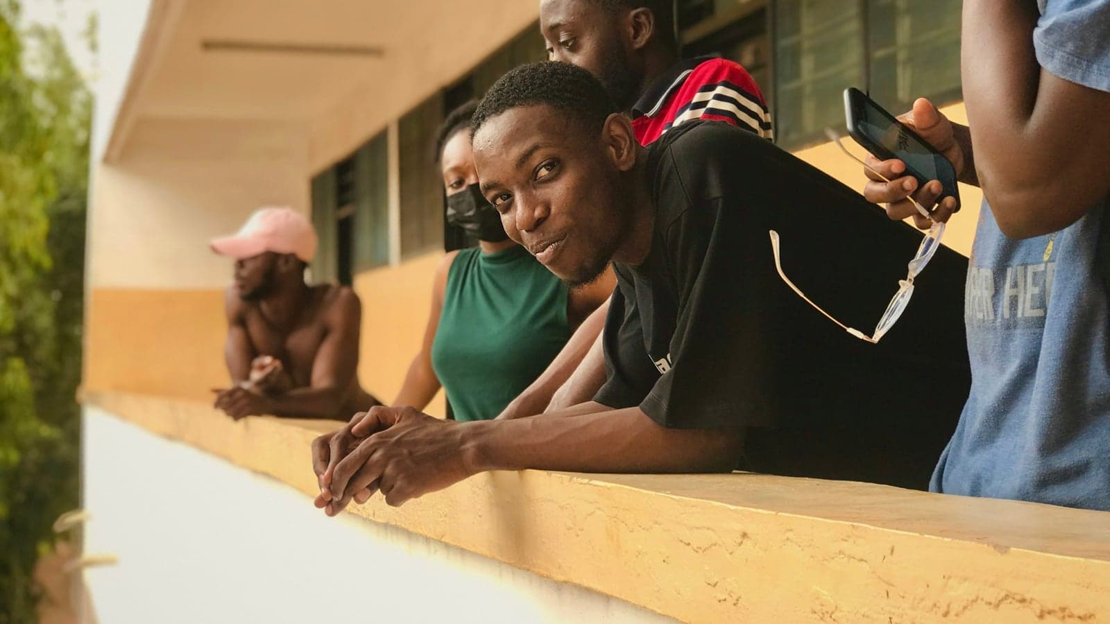 Nigerian university students leaning on a campus balcony